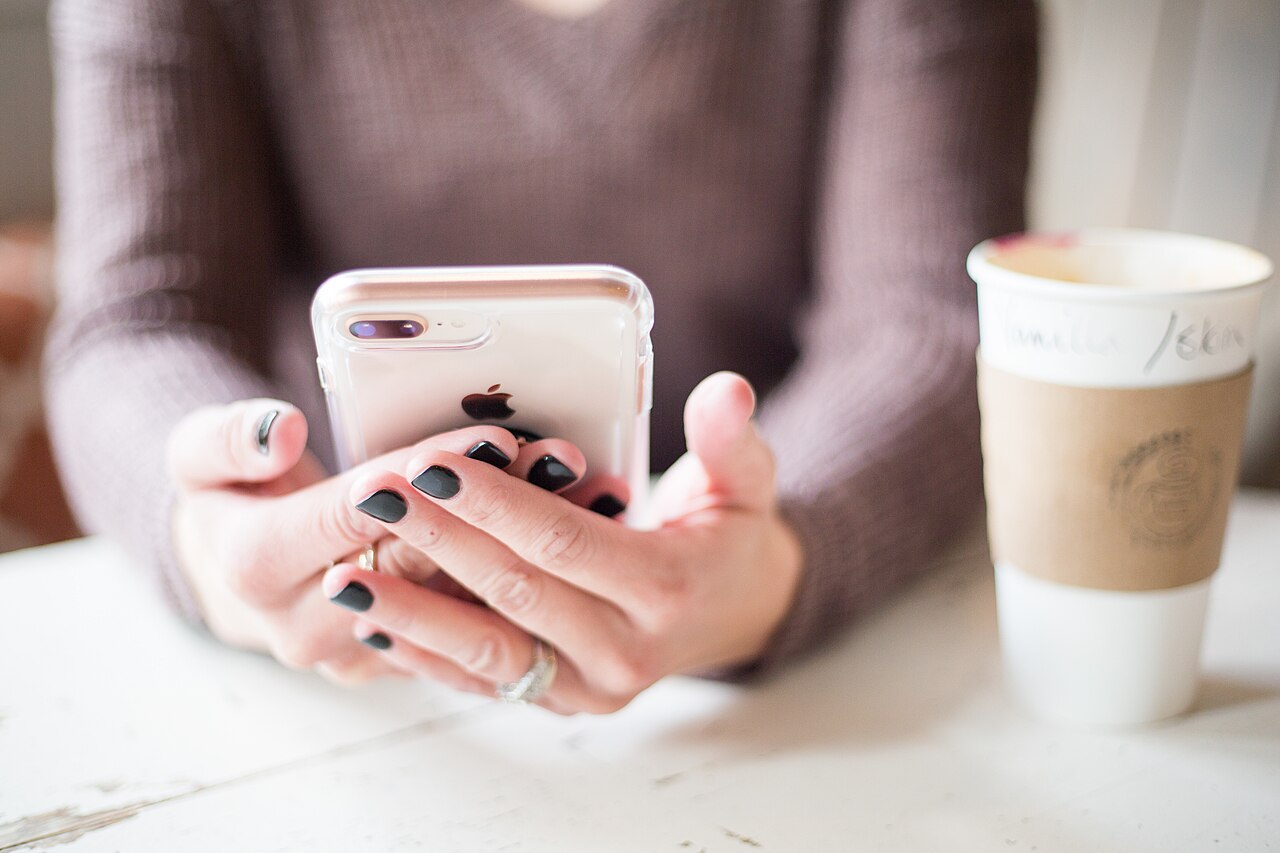 Woman holding an iPhone for an iPhone 18 price estimate article